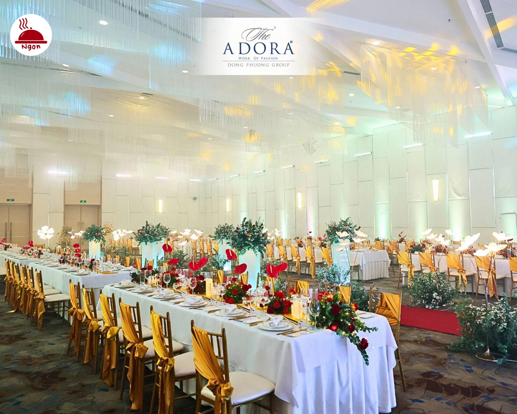 Không gian tổ chức sự kiện sang trọng tại The ADORA, với dãy bàn tiệc dài được trang trí công phu bằng hoa, nến và đồ dùng ăn uống cao cấp, sàn trải thảm họa tiết