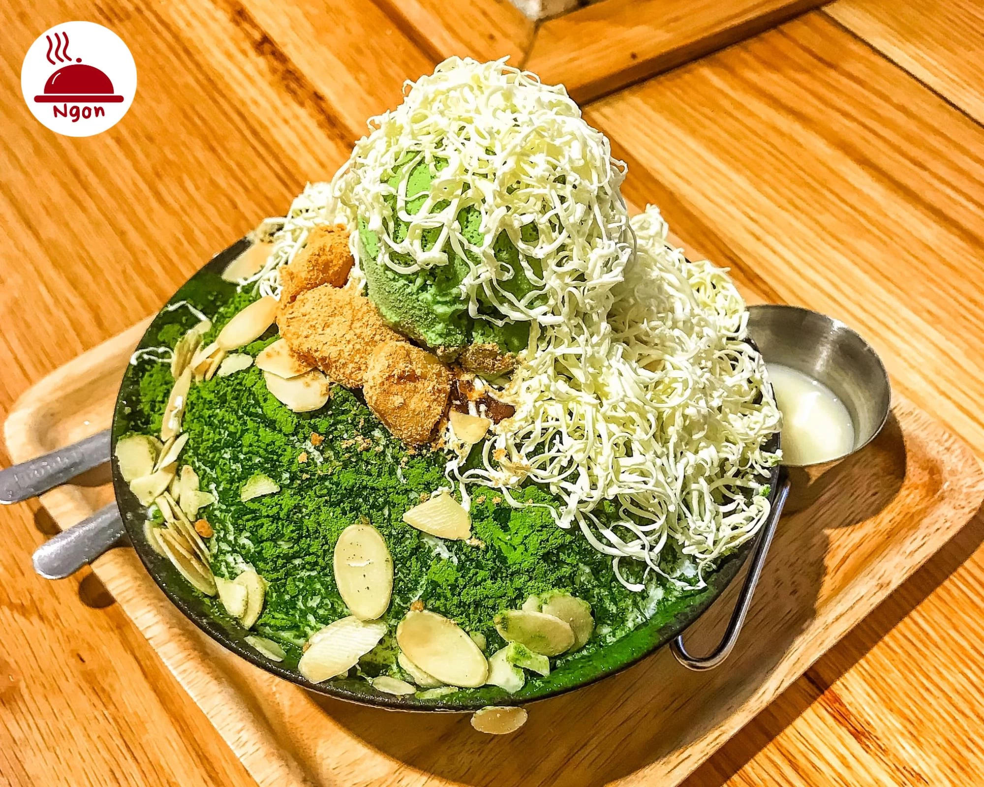 Matcha Bingsu với lớp phô mai bào sợi và hạnh nhân rắc đều - một sự kết hợp hoàn hảo của vị chát nhẹ và béo ngậy