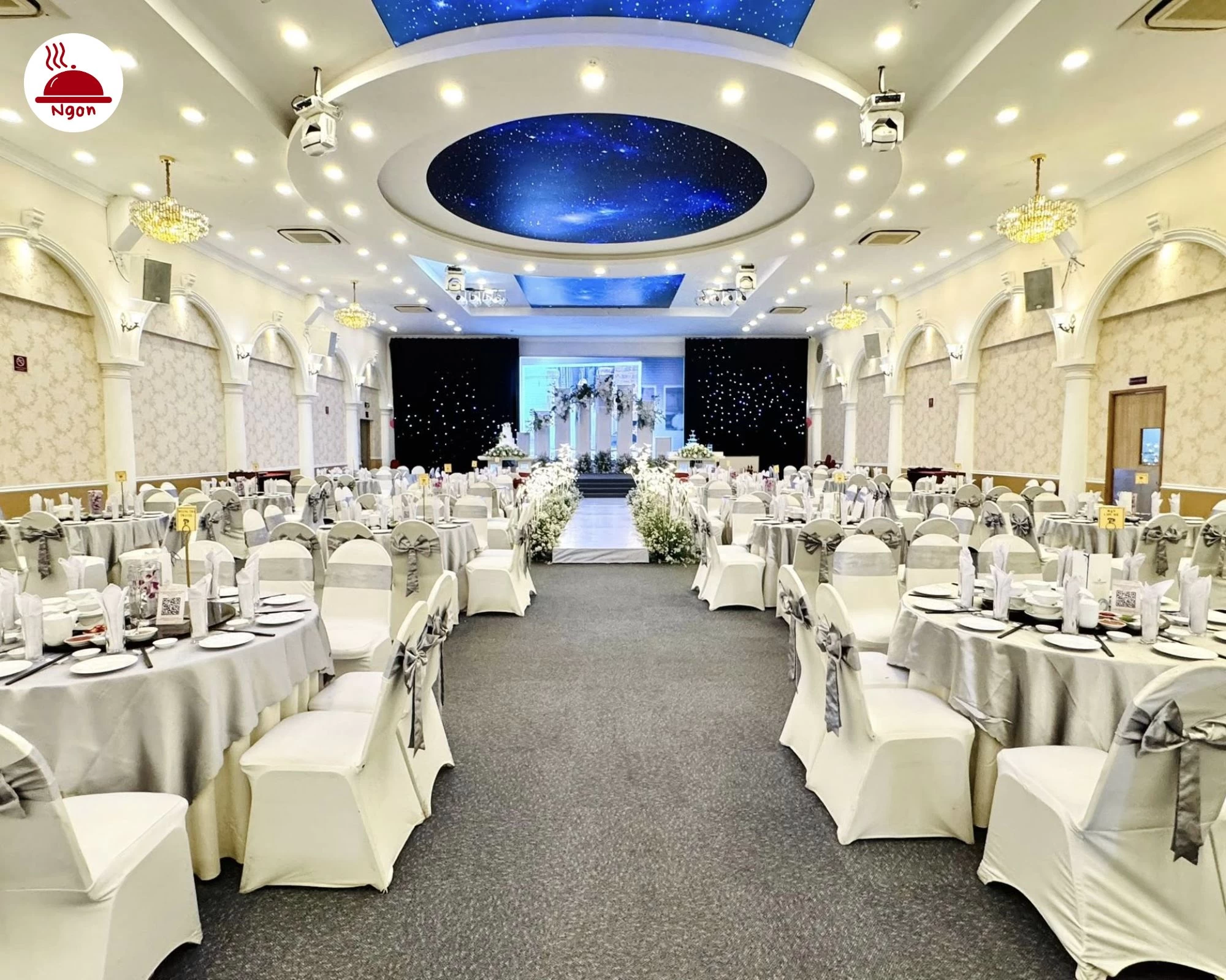 Toàn cảnh sảnh tiệc Á Đông Riverside với lối đi thảm xám dẫn đến sân khấu cưới được trang hoàng lộng lẫy