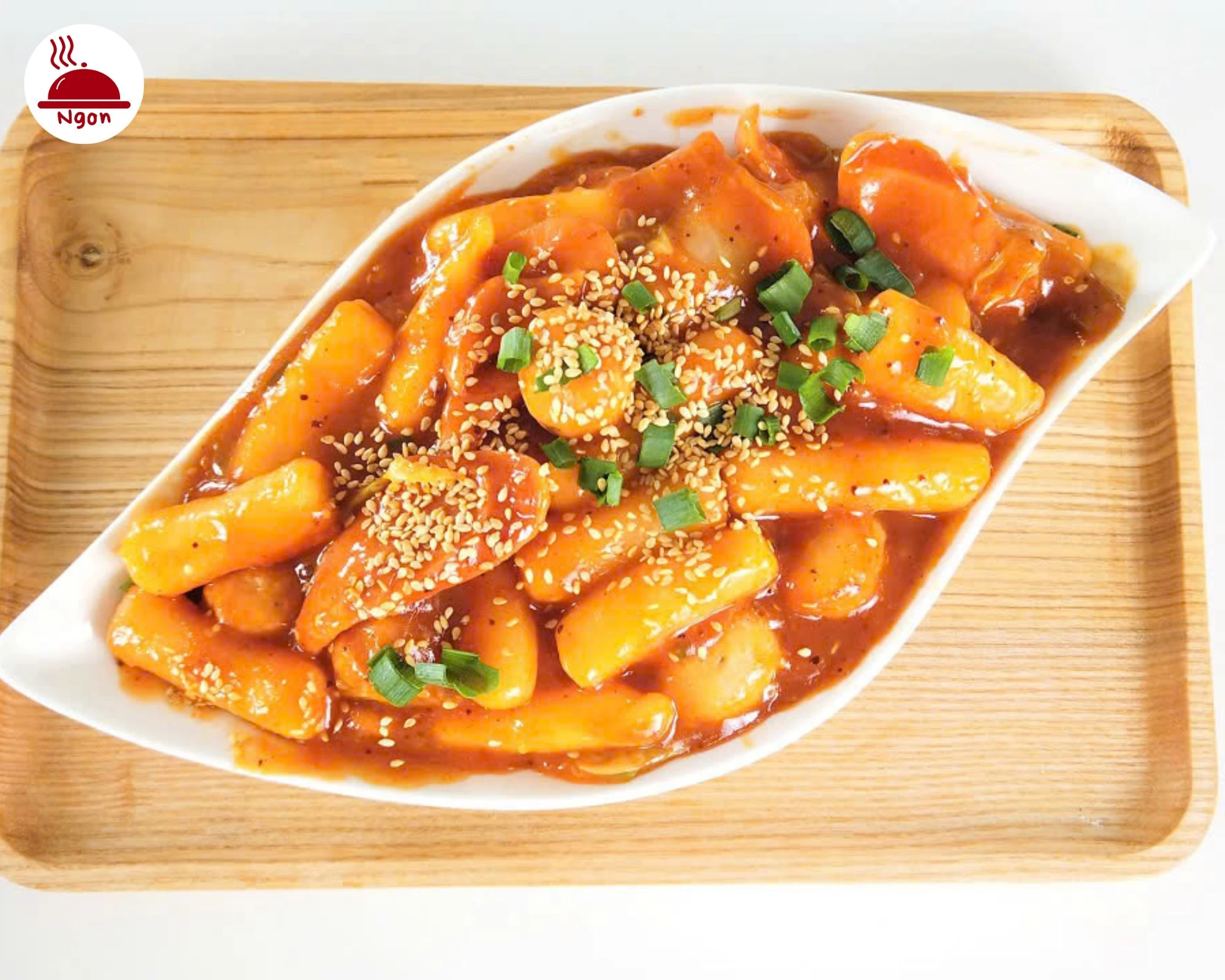 Bánh gạo cay Hàn Quốc với màu sốt đỏ tươi, rắc vừng và hành lá, sẵn sàng thưởng thức