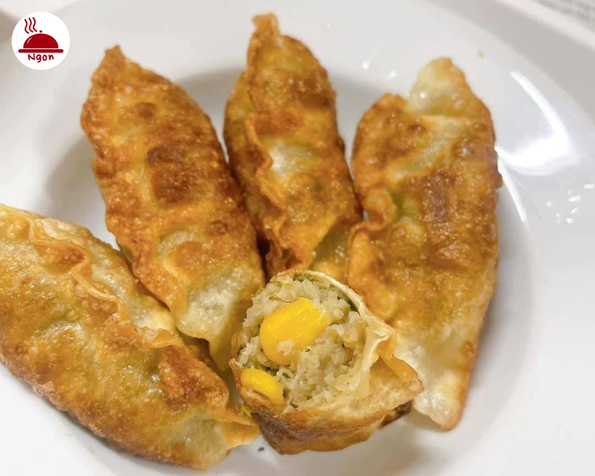 Đĩa bánh mandu chiên nóng hổi, một miếng bánh cắt đôi để lộ nhân đầy màu sắc và hấp dẫn