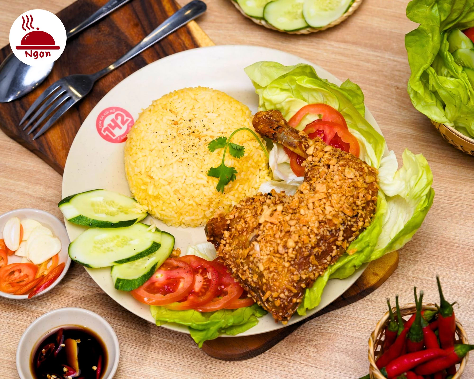Đĩa cơm gà xối mỡ của Quán 142, đầy đủ rau sống, dưa leo và nước chấm đặc biệt